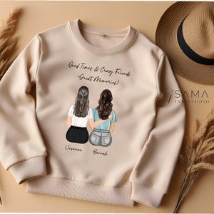 May include: A beige sweatshirt with a graphic of two women sitting back to back. The text on the sweatshirt reads "Good Times & Crazy Friends - Great Memories!" and includes the names "Susanna" and "Hannah".