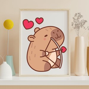 May include: A framed print featuring a cartoon capybara holding a bow and arrow with a heart-shaped arrow. Two red hearts are above the capybara. The artwork has a light brown and pink color scheme, perfect for Valentine's Day or a nursery.