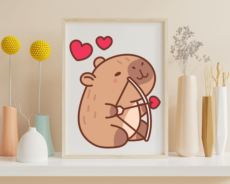 May include: A framed print featuring a cartoon capybara holding a bow and arrow with a heart-shaped arrow. Two red hearts are above the capybara. The artwork has a light brown and pink color scheme, perfect for Valentine's Day or a nursery.