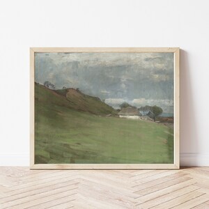 Puede incluir: Una pintura de un paisaje rural con una peque&ntilde;a casa blanca en la distancia. El cielo est&aacute; nublado y la hierba es verde. La pintura est&aacute; enmarcada en un marco de madera claro.