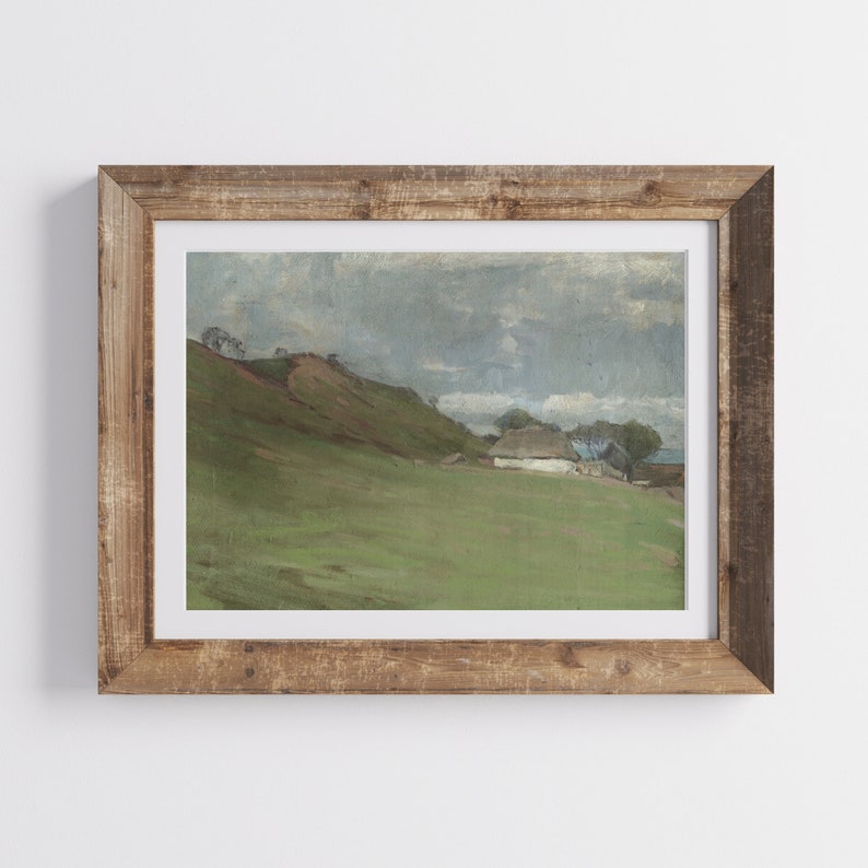 Puede incluir: Una pintura enmarcada que representa un paisaje rural con una peque&ntilde;a casa blanca con techo de paja, ubicada en un campo verde al pie de una colina. El cielo est&aacute; cubierto de nubes grises.