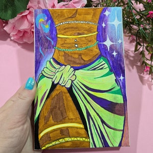 Peut inclure: Une peinture représentant le torse d'une personne à la peau brune. La personne porte un sarong vert et violet et plusieurs colliers de perles dorés et verts. L'arrière-plan est un dégradé de violet et de bleu avec des étoiles blanches.