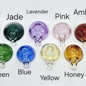 May include: Ten glass bowl attachments in a range of colours: smoke, jade, lavender, pink, amber, green, blue, yellow, honey, and clear. Each bowl has a rounded top and a clear glass stem.