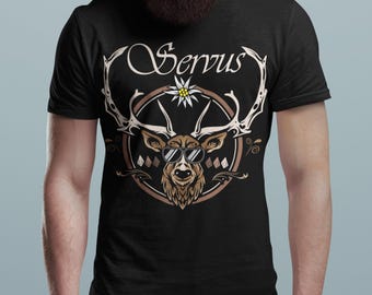 May include: Black t-shirt with a brown deer wearing sunglasses and a white flower on its antlers. The text "Servus" is written in a cursive font above the deer.