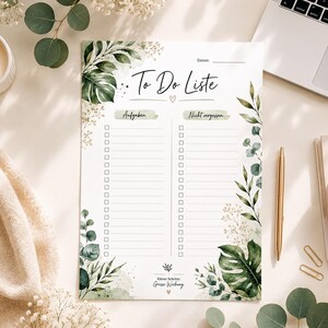 Könnte beinhalten: Ein weißer To-Do-Listen-Notizblock mit grünen botanischen Illustrationen und dem Text "To Do Liste". Der Notizblock hat Abschnitte für Aufgaben und Erinnerungen, mit einem goldenen Stift und einem Laptop im Hintergrund.