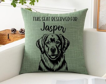 May include: Green decorative throw pillow with the text "THIS SEAT RESERVED FOR Jasper" and a black illustration of a Labrador Retriever dog. The pillow is on a white couch.