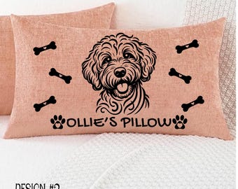 May include: A peach-colored rectangular pillow with a black illustration of a dog's face, paw prints, and bone shapes. The text "Ollie's Pillow" is below the dog's face. The words "Design #2" are at the bottom.