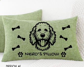 May include: A rectangular sage green pillow with a black dog face design, paw prints, and bone accents. The text "NERO'S PILLOW" is below the dog's face. The words "DESIGN #1" are at the bottom.