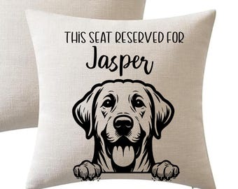 May include: Beige square throw pillow with a black graphic of a Labrador Retriever dog and the text "THIS SEAT RESERVED FOR Jasper". The dog illustration includes the dog's head, paws, and tongue.