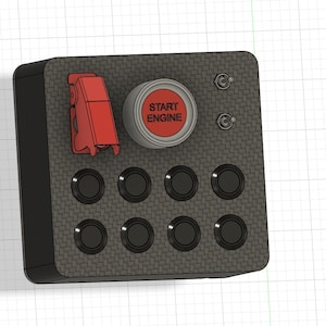 May include: A black and gray control panel with a carbon fiber texture. It features a red "START ENGINE" button, a red toggle switch, two silver toggle switches, and eight black buttons. The panel is rectangular with rounded corners.