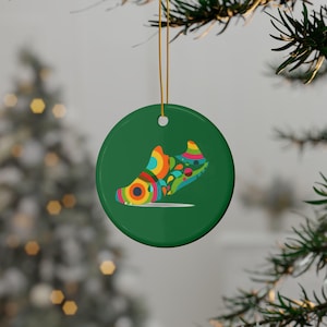 May include: A green round Christmas ornament with a colorful abstract shoe design.