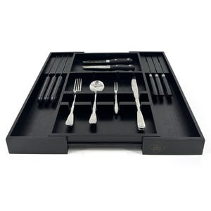 Könnte beinhalten: Eine schwarze Besteckschublade aus Holz mit mehreren Fächern, die verschiedene Silberbestecke enthält. Das Besteck umfasst Messer, Gabeln, Löffel und einen Servierlöffel. Das Tablett dient zum Ordnen und Aufbewahren von Besteck.