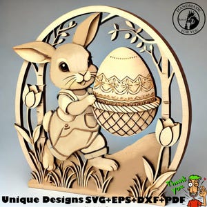 Puede incluir: Un recorte de madera de un conejito sosteniendo un huevo de Pascua decorado en una cesta. El conejito lleva un mono y está rodeado de flores y hojas. El recorte tiene forma de círculo y tiene una etiqueta "Handmade for You" en la esquina superior derecha.