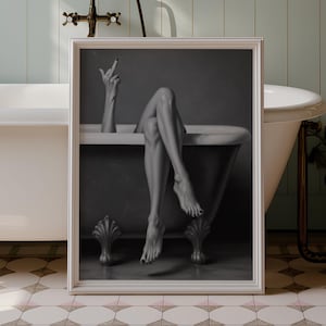 May include: A framed monochrome photograph of a person in a bathtub, with legs and an arm visible. The bathroom features a claw-foot tub, floral wallpaper, and a vintage tap.