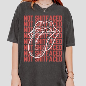 May include: Black oversized t-shirt with a white tongue graphic and the text "NOT SHITFACED" repeated in red.