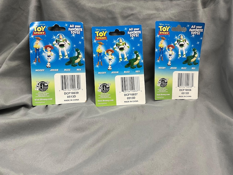 K&ouml;nnte beinhalten: Drei Toy Story Charakter-Sammelkarten mit Woody, Jessie, Buzz Lightyear und Rex. Die Karten sind blau, gr&uuml;n und rot mit dem Text "All your favorite toys!" und "Toy Story".