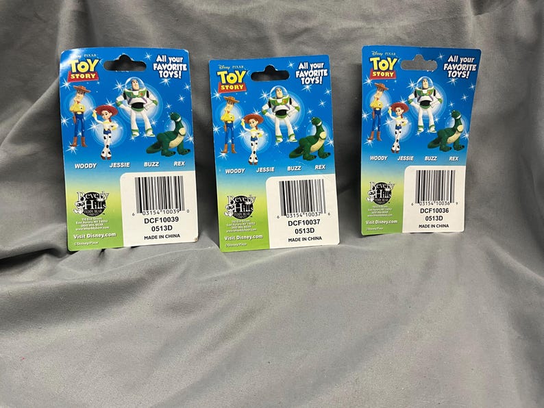 K&ouml;nnte beinhalten: Drei Sammelkarten mit Toy Story-Charakteren, die Woody, Jessie, Buzz Lightyear und Rex zeigen. Die Karten sind blau, gelb und rot mit dem Text "All your favorite toys!" und "Toy Story".