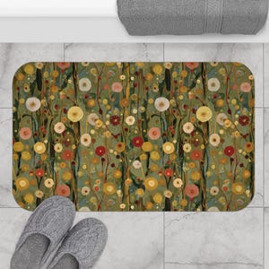 May include: A rectangular bath mat with a floral design in shades of green, yellow, red, and pink. The pattern resembles a stylized meadow with various flower shapes and stems. The mat is placed on a tiled floor.