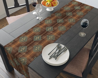 Puede incluir: Un camino de mesa con estampado marrón y verde sobre una mesa de madera oscura. El camino de mesa tiene un diseño de cuadros con detalles florales. Un cuenco blanco con manzanas, copas de vino y un plato con cubiertos también están sobre la mesa.