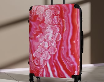 Può includere: Una valigia rossa e rosa con motivo floreale. La valigia ha un manico e una cornice neri ed è progettata per i viaggi. Il motivo floreale è bianco e rosa, creando un effetto visivo sorprendente. Misura circa 76 cm di altezza.