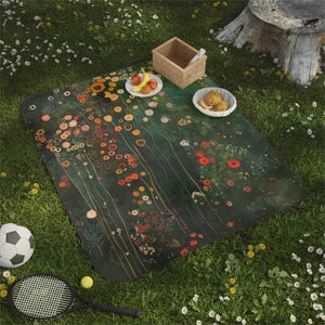 Könnte beinhalten: Eine Picknickdecke mit floralem Design in Grün-, Orange- und Rottönen liegt auf einer Wiese. Ein Fußball, ein Tennisschläger und ein Korb mit Essen befinden sich in der Nähe. Die Decke hat einen dunkelgrünen Hintergrund mit bunten Blumen.