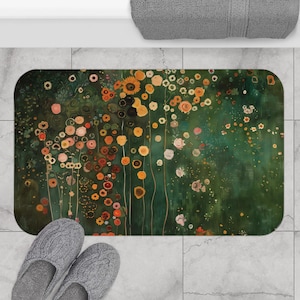 Puede incluir: Alfombra de baño rectangular con un diseño floral en tonos verdes, amarillos, naranjas y rosas. La obra de arte se asemeja a una pintura con un fondo verde oscuro y varias formas de flores. Se ven zapatillas grises en la parte inferior.