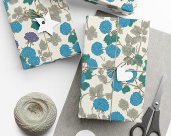 May include: Three wrapped gifts with floral patterned paper in blue, teal, and gray. Each is tied with twine and a white tag. A ball of twine, scissors, and blank tags are also visible.