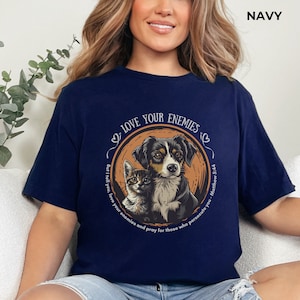 May include: A navy blue t-shirt with a graphic of a dog and cat with the text "Love your enemies" and "Matthew 5:44" in a circle.