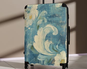 Könnte beinhalten: Ein Rollkoffer mit blauem und weißem Blumendesign. Der Koffer hat einen schwarzen Griff und schwarze Räder. Das Blumenmuster zeigt große, stilisierte weiße Blumen und fließende Formen auf einem strukturierten blauen Hintergrund.