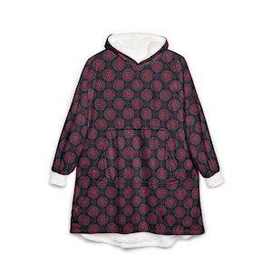 May include: A hooded blanket with a repeating pattern of red and teal circles on a dark background. The interior hood and cuffs are white. The blanket has a large front pocket.