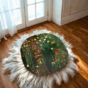 May include: A round floor pillow with a floral design in shades of green, orange, and red. The pillow is placed on a fluffy, white faux fur rug, set on a hardwood floor. The pillow's design resembles a painting.