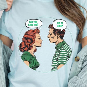 May include: A light blue t-shirt with a comic book style graphic of a woman with red hair and a man with brown hair. The woman is saying "Can you save me?" and the man is saying ".xls or .xlsx?"