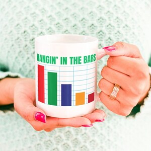 May include: White ceramic coffee mug with a bar graph design and the text "Hangin' in the bars". The bars are red, green, blue, orange, and red.