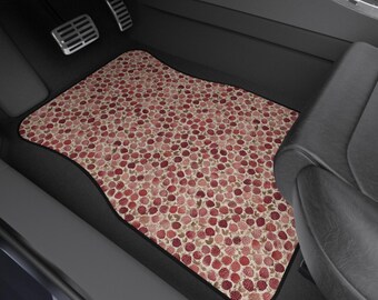 May include: Car floor mat featuring a pattern of red and pink berries on a beige backdrop. The mat, with a black edge, is positioned in the driver's side footwell of a car, close to the pedals.