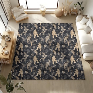 May include: A large rectangular area rug with a dark blue background and a repeating pattern of Bigfoot figures and beige foliage. The rug is placed in a living room setting with furniture and natural light.