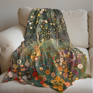 May include: A soft, green throw blanket with a floral pattern. The blanket features a watercolor-style design of trees and flowers in shades of red, yellow, orange, and purple.
