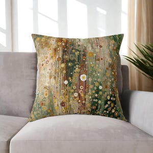 May include: Square decorative pillow with an abstract design. The pillow features a pattern of overlapping circles in shades of green, yellow, brown, and white. The pillow is placed on a gray sofa, creating a neutral backdrop for the colorful design.