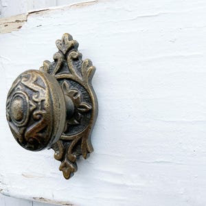 May include: A decorative antique-style door knob with a detailed floral design. The knob is made of metal and has a brass finish.