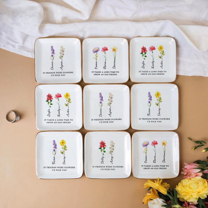 Pu&ograve; includere: Nove porta anelli in ceramica bianca con bordo dorato e disegni floreali. Ogni porta anelli presenta un diverso arrangiamento floreale e un messaggio personalizzato. I messaggi includono nomi e citazioni sull'amicizia.