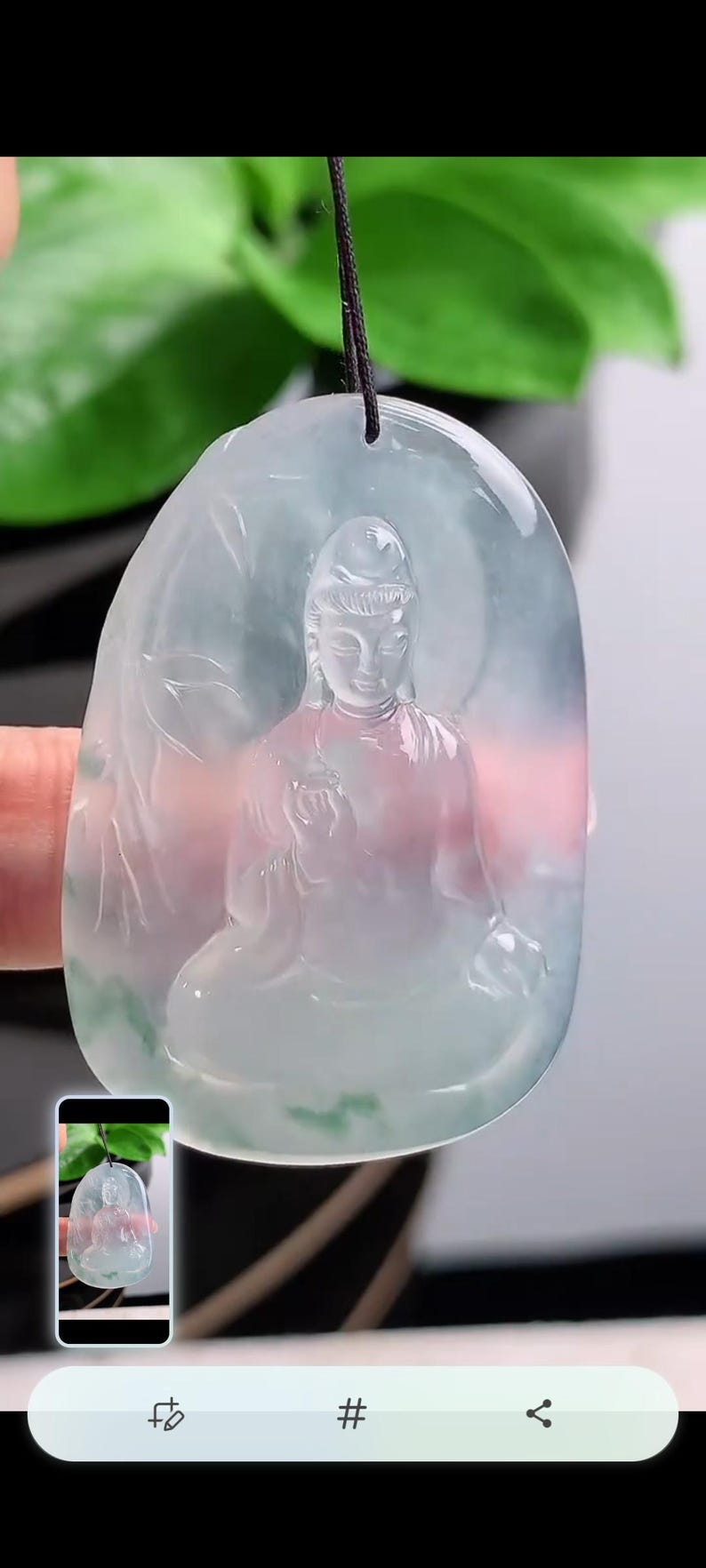 May include: A translucent jade pendant carved with a seated Buddha figure. The pendant is light green with pink and white hues, suspended from a black cord. The Buddha is depicted in a meditative pose.