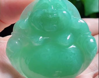 May include: A translucent, bright green carved pendant depicting a laughing Buddha figure with a rounded belly and smiling face. The smooth, polished stone features a vibrant emerald hue with subtle variations in colour intensity throughout the piece.