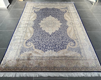 May include: A blue and cream patterned rug with a floral design in the center. The rug has a fringe border.