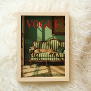 K&ouml;nnte beinhalten: Ein gerahmter Wandkunstdruck mit einem Geparden, der auf einem gr&uuml;n-wei&szlig; gestreiften Sofa ruht. Das Wort VOGUE ist oben in fetten roten Buchstaben gedruckt. Die Szene zeigt einen Raum mit gr&uuml;nen W&auml;nden, einem dunklen Holzrahmen und einem Bild.
