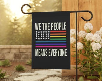 Puede incluir: Una bandera de jardín negra con un diseño de bandera estadounidense arcoíris y el texto "We the People Means Everyone".