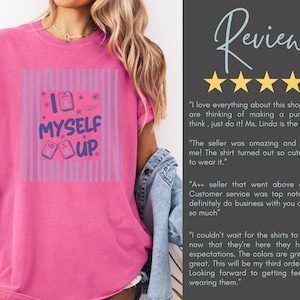 May include: A bright pink t-shirt featuring a graphic design with vertical light blue stripes and the text "I MYSELF UP" in dark blue lettering. The design includes small rectangular icons and star shapes. The shirt has a crew neckline and short sleeves.