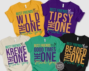May include: A collection of colorful t-shirts with Mardi Gras-themed text. Each shirt features the phrase "Best Friends" above a unique word like "Wild," "Tipsy," or "Beaded," followed by "The One" and "Mardi Gras." Colors include yellow, purple, green, black, and cream.