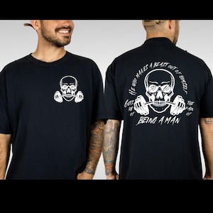 May include: Black t-shirt with a white skull graphic holding dumbbells. The text on the back of the shirt reads "He who makes a beast out of himself gets rid of the pain of being a man."