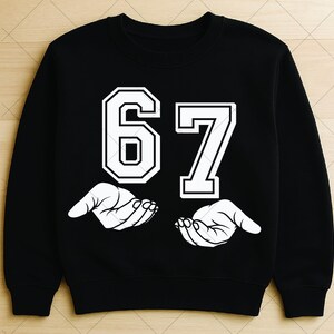 May include: Black sweatshirt with the number 67 in white, outlined in black. Below the numbers are two white hands, palms up. The sweatshirt is a crew neck style.