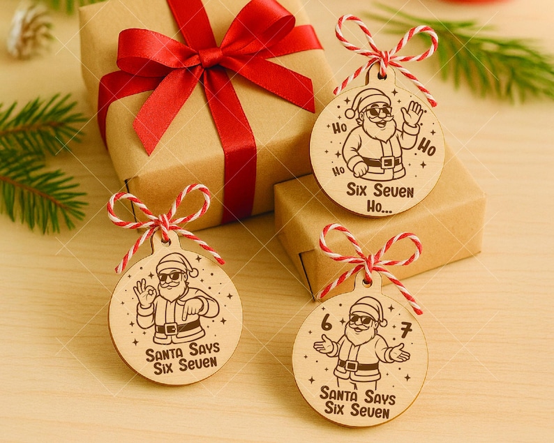 以下が含まれることがあります： サンタクロースのイラストと「Santa Says Six Seven」の文字が入った木製のクリスマスオーナメント。丸いオーナメントは赤と白の紐で結ばれています。背景には赤いリボンが付いたギフトボックスがあります。