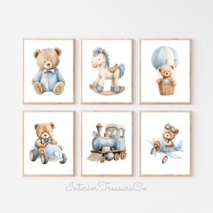 May include: Six framed watercolour prints depicting a teddy bear in different settings. The prints show a teddy bear in a blue outfit, on a rocking horse, in a hot air balloon, driving a car, on a train, and flying a plane. The prints are in wooden frames.